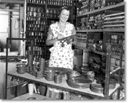 Woman marking pottery in a storage room containing numerous completed pottery items, c. 1930